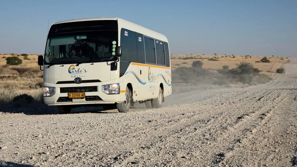 Carlo’s Shuttle & Tours coach travelling on a Namibian desert road